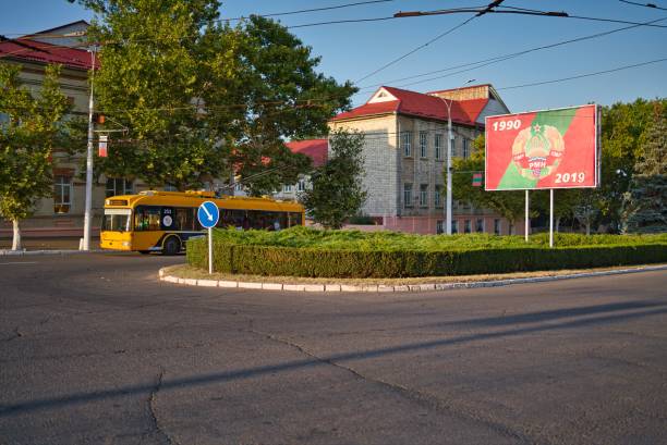 Tiraspol, Transnistria - August 31, 2019: Empty street with a bus in Tiraspol, Transnistria, in the sunlight afternoon and a big sign with the years since Transnistria gained independence.