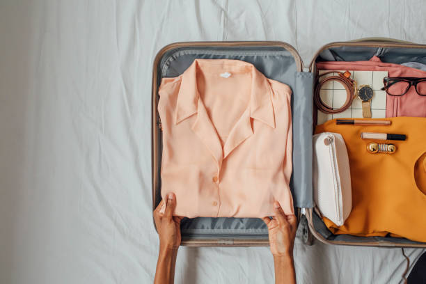 A Woman Packing her Clothes in a Suitcase Hands of unrecognisable woman putting elegant blouse in a suitcase. suitcase stock pictures, royalty-free photos & images
