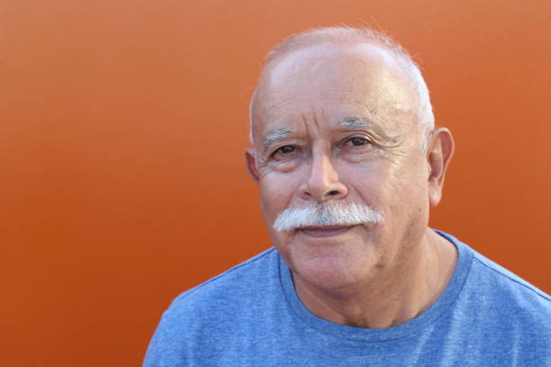 Senior Hispanic man in orange background.