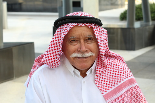 Gray haired Arabic man with a mustache.