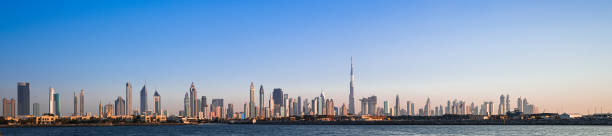 солнце садится над городом огней - dubai skyline panoramic united arab emirates стоковые фото и изображения