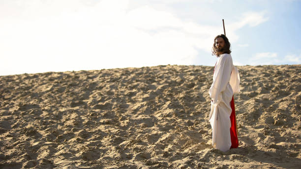 istock Hermit with staff walking in desert looking to camera, asceticism and fasting 1175583407