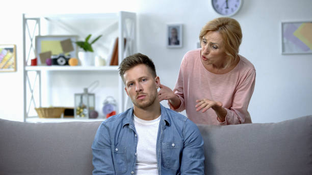 Mother scolding adult son sitting at home on sofa, unfulfilled moms dreams Mother scolding adult son sitting at home on sofa, unfulfilled moms dreams mother in law stock pictures, royalty-free photos & images