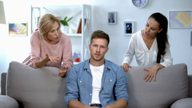 istock Irritated man sitting on sofa, listening wife and mother reproach, problem 1175583502