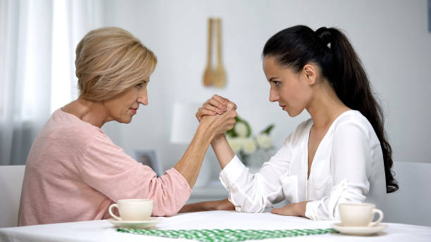 Mother and daughter-in-law looking on each other during arm wrestling battle Mother and daughter-in-law looking on each other during arm wrestling battle mother in law stock pictures, royalty-free photos & images