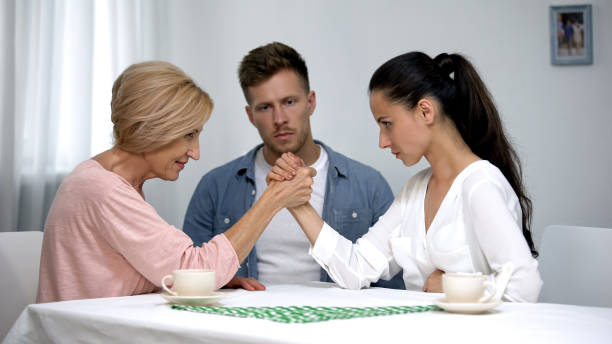 Man looking at mother and wife during arm wrestling competition, family fight Man looking at mother and wife during arm wrestling competition, family fight mother in law stock pictures, royalty-free photos & images