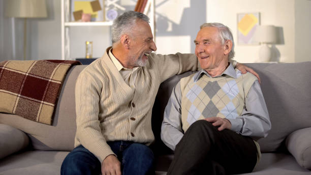 istock Smiling senior men looking each other sitting home sofa friendship communication 1175584451