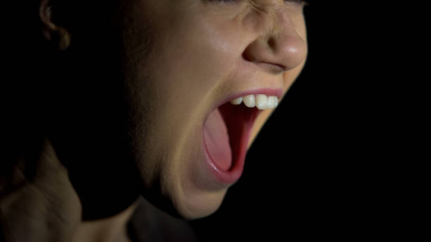 istock Face of female screaming against dark background, psychological problems 1175584501