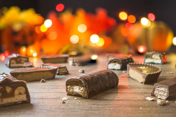 Cut pieces of candy bars with a Halloween background Pieces of chocolate candy bars with light bokeh in the background. halloween candy stock pictures, royalty-free photos & images