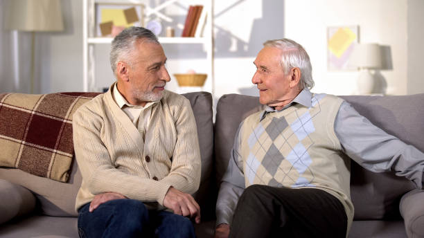 istock Positive senior men looking each other sitting home sofa, friendship emotions 1175585155