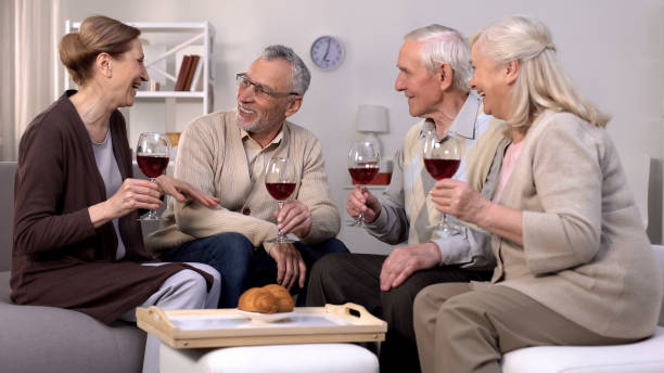 istock Cheerful elderly friends with wine glasses talking relaxing home, leisure time 1175585185