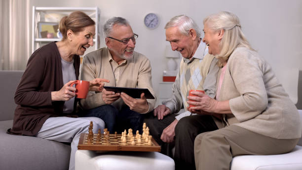 istock Smiling pensioners watching online video tablet together, playing chess, hobby 1175585204