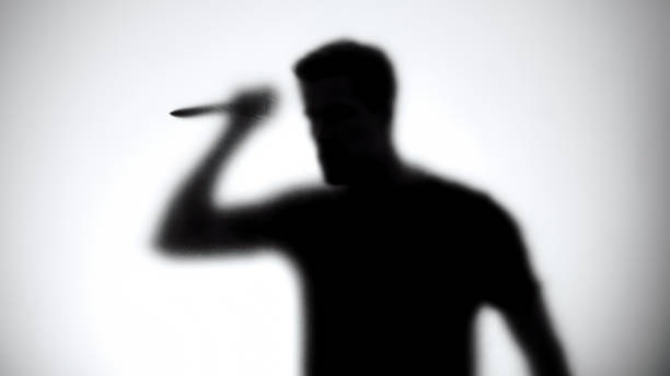 Silhouette of a man with knife standing behind glass wall, thriller Silhouette of a man with knife standing behind glass wall, thriller serial killings photos stock pictures, royalty-free photos & images