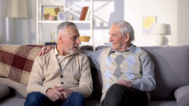 istock Two old friends talking having fun sitting on sofa, positive mood, conversation 1175586498