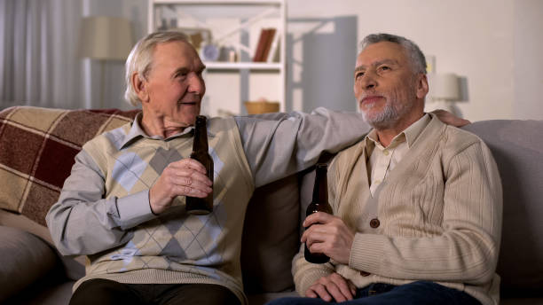 istock Two aged men relaxing on sofa with beer bottles, friendship communication, fun 1175587053
