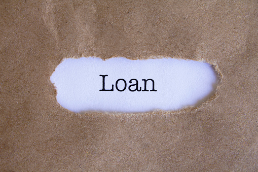 A close-up shot of the word Loan, under torn brown paper.