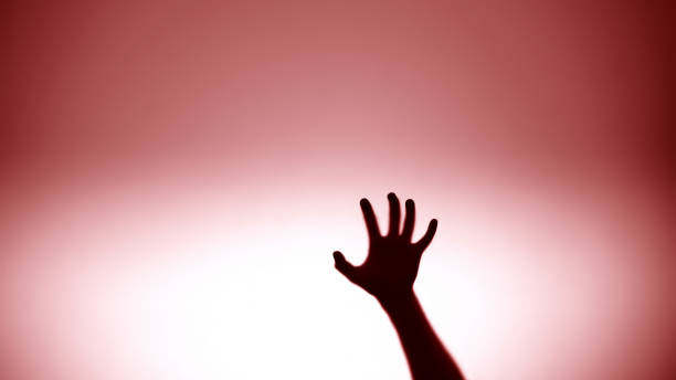 istock Hand sliding down on glass, red flashlight on background, crime scene, murder 1175587620