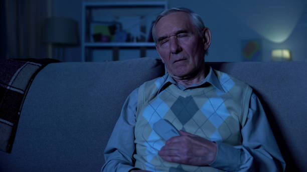 istock Elderly man holding remote controller sleeping in front of TV, evening at home 1175587624