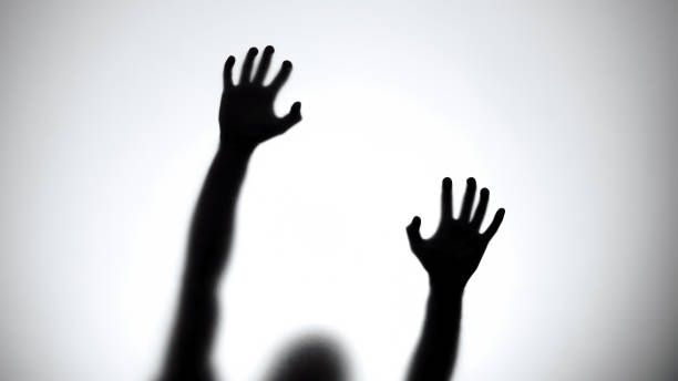 istock Shadow behind glass wall trying to get out, escape, red lights background 1175587706