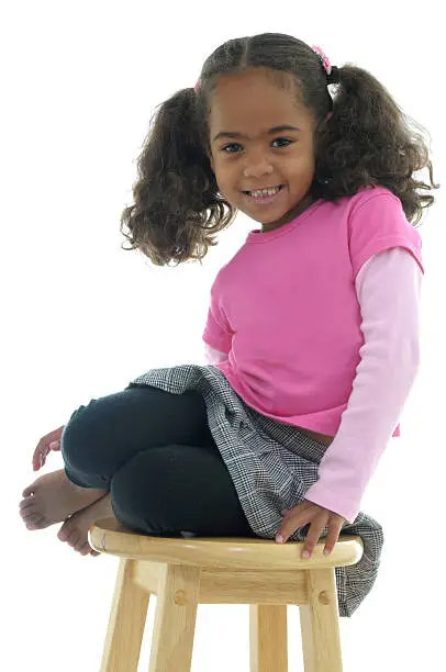 Little girl smiling on a stool.