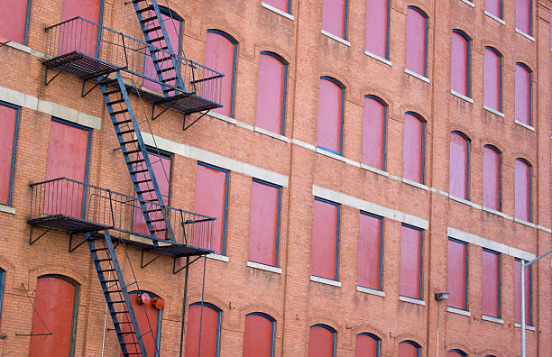 istock red house wall with boarded-up windows and fire escape ladder 117559731