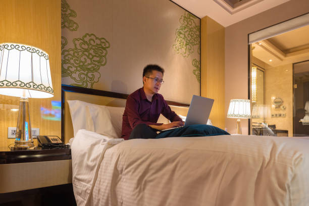 istock Businessman on bed working with a laptop from his hotel room 1175598284