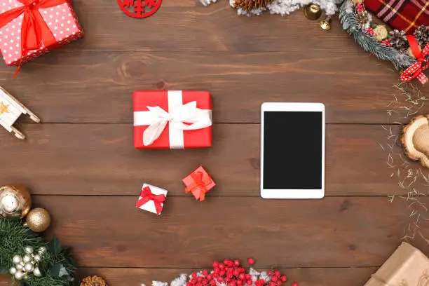 Photo of New Year. Digital tablet and presents isolated on table top view close-up