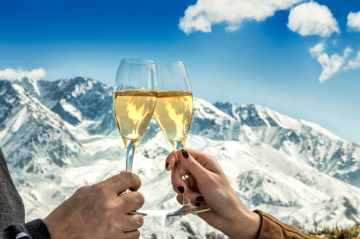 Celebration with sparkling wine at foot of the snowy mountain.