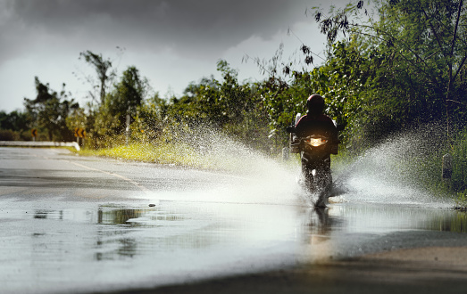 Motorcycle run through flood water after hard rain with water spray from the wheels .Stop action ( capture with the high speed shutter) and selective focus.