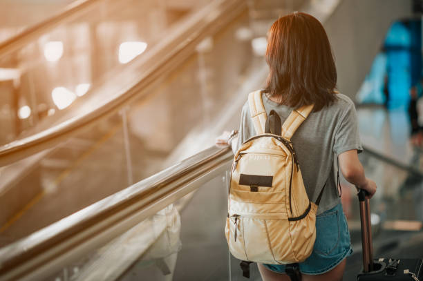 istock Young woman pulling suitcase in modern airport terminal. Travelling guy with his luggage while waiting for transport. Rear view. Copy space 1175626505