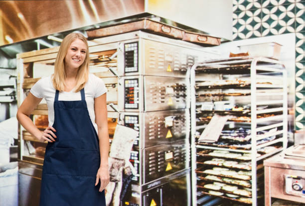 one person / waist up of blond hair caucasian female / young women baker / caterer / retail occupation cooking / preparing food / standing at the bakery / restaurant in the store wearing apron / uniform / t-shirt / shirt and celebration / retail - thank you excitement waist up horizontal imagens e fotografias de stock