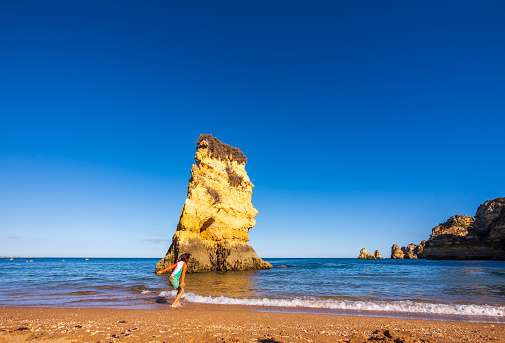 Praia Dona Ana is a popular beach cove near Lagos in the Algarve area of Portugal. The stunning beach is surrounded by imposing, colorful cliffs, stunning rock formations and the clear turquoise waters of the Atlantic Ocean.