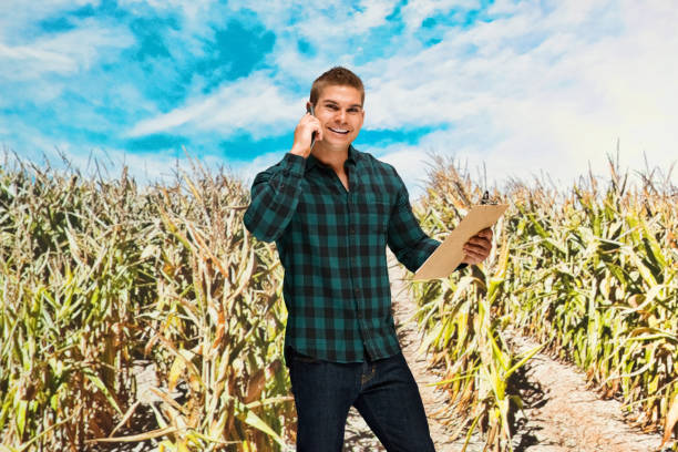 Waist up / one man only / one person of 20-29 years old adult handsome people caucasian male / young men farmer / farm worker standing wearing button down shirt / shirt / jeans who is smiling / happy / cheerful / talking and holding mobile phone / clipboard / document / paperwork / contract / to do list / using smart phone cintura para arriba / un hombre solamente / una persona de 20-29 años de edad adulto guapo personas caucásicas hombres / hombres jóvenes granjero / trabajador de la granja de pie con botón hacia abajo camisa / camisa / jeans que es sonriente / feliz /