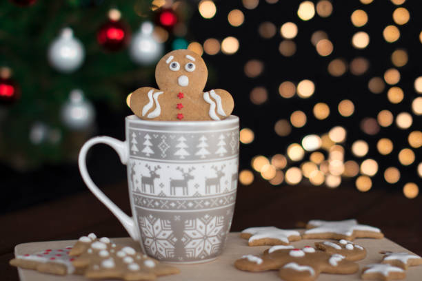 gingerbread man cookie in a cup with hot drink with christmas lights on a background
