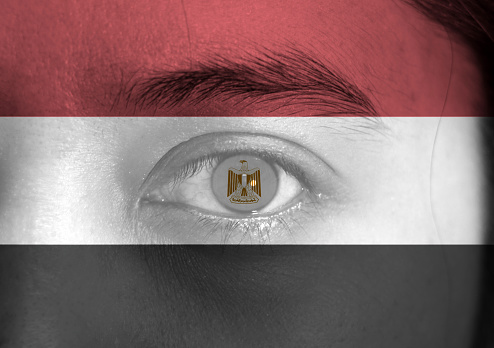 Human face painted Egyptian flag with eagle on the center of eye or eyeball. Human eye painted with flag of Egypt.