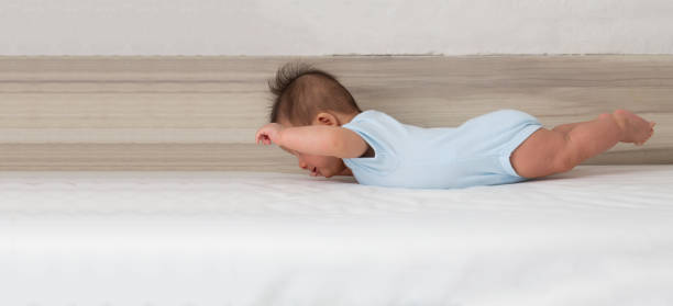 bebé bebé levantar el pecho y a veces las piernas hacia arriba con los brazos levantados hacia los lados, acción de las habilidades del bebé y el niño pequeño concepto. tres meses de edad - arms lifted fotografías e imágenes de stock