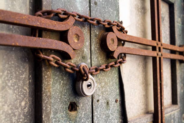 Old metallic padlock with rusty vintage chain hangs on old door, security concept stock photo