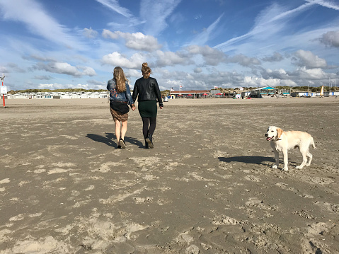 Mother with Daughter and dog having a Beach walk on a late summer day