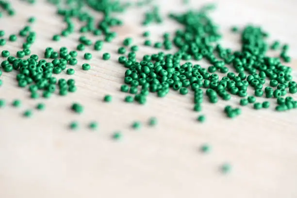 Closeup of green seed beads scattered on a wooden surface