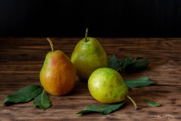 istock Three fresh pears with leaves lie on a wooden table 1175649208