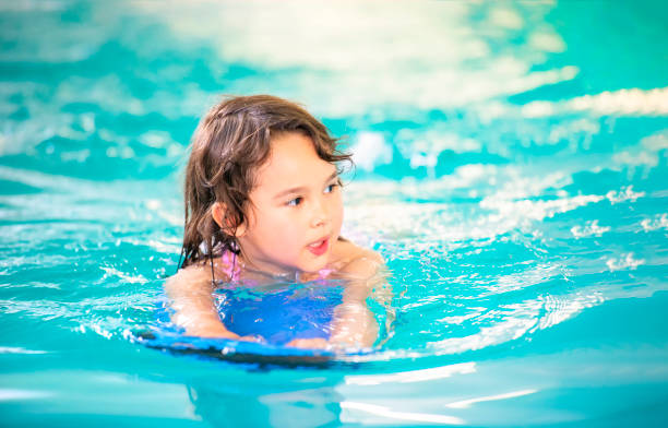 istock Smiling girl has fun with floating board in swimming pool 1175650831