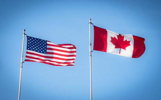 The Canadian and American flags fly together.