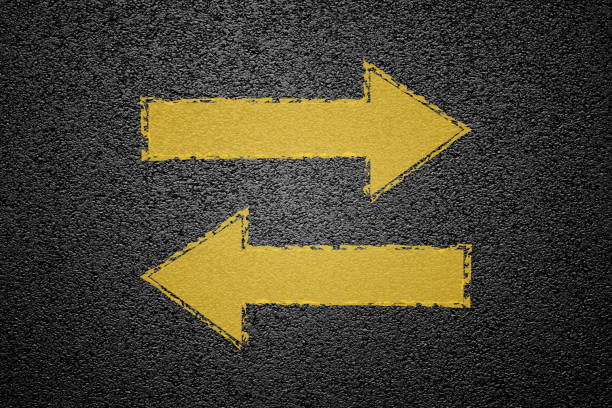 Round trip yellow arrow signs on asphalt ground