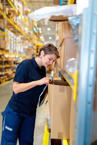istock Woman checking content of cardboard box on warehouse racks 1175660488