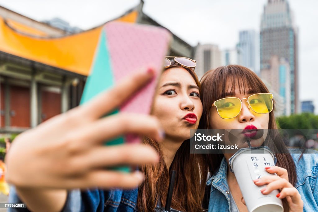 Female friends pouting while taking selfie in city Female friends puckering while taking selfie. Young women are making memories in city. They are spending leisure time together. 20-24 Years Stock Photo