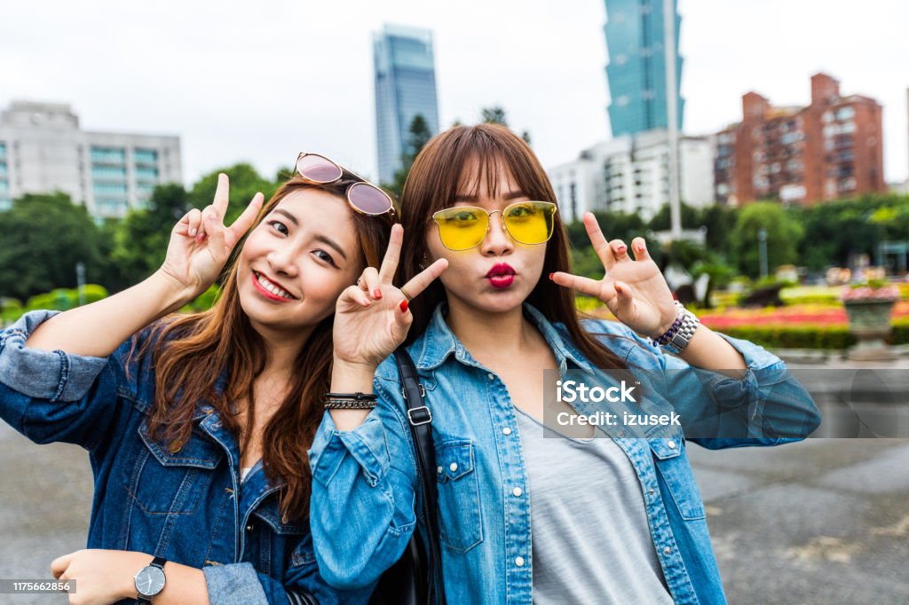 Portrait of happy friends gesturing in city Portrait of happy female friends gesturing while standing in city. Cheerful fashionable young women in denim jackets. They are spending weekend together. Outdoors Stock Photo