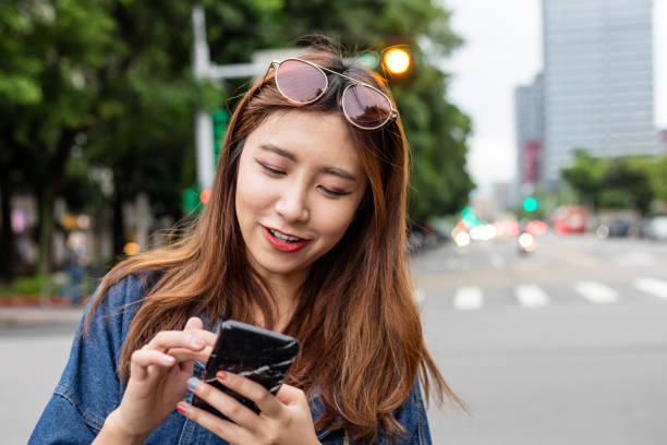 istock Smiling young woman using smart phone in city 1175663538
