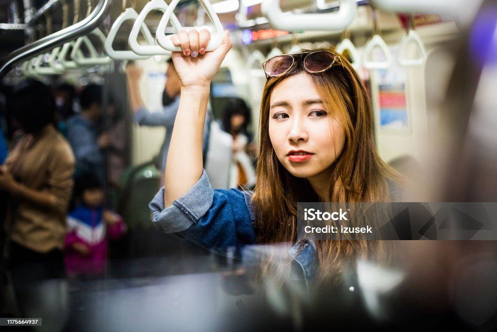 Female passenger traveling in subway train Female passenger traveling in subway train. Thoughtful woman is looking away during journey. She is on weekend. Asian and Indian Ethnicities Stock Photo