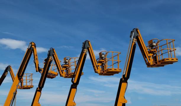 istock Aerial work platforms lined up against blue sky with clouds 1175665707