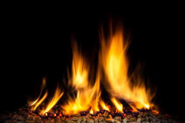 burning wood pellets, visible flame and dark background. biomass and fuel concept.